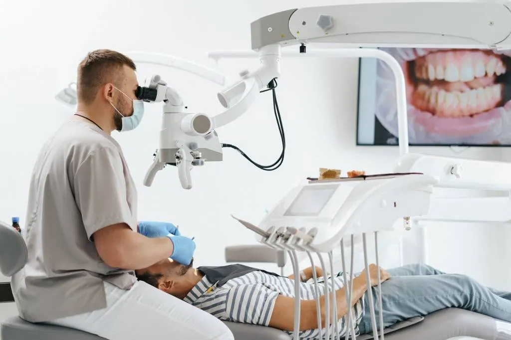 young-man-with-patient-bib-dental-chair-dentist-who-sits-him-he-looks-his-teeth-using-dental-microscope-holds-dental-bur-mirror_158595-7731.jpg young-man-with-patient-bib-dental-chair-dentist-who-sits-him-he-looks-his-teeth-using-dental-microscope-holds-dental-bur-mirror_158595-7731.jpg